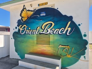A building with a mural of a butterfly and the words 'Orient Beach' on the side.