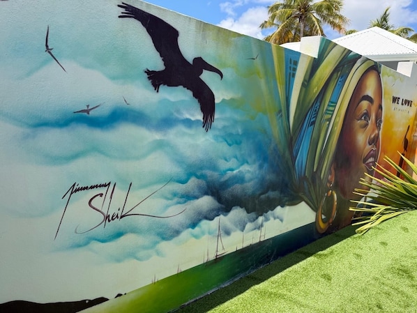 A mural with a bird, clouds, and a partial view of a face.