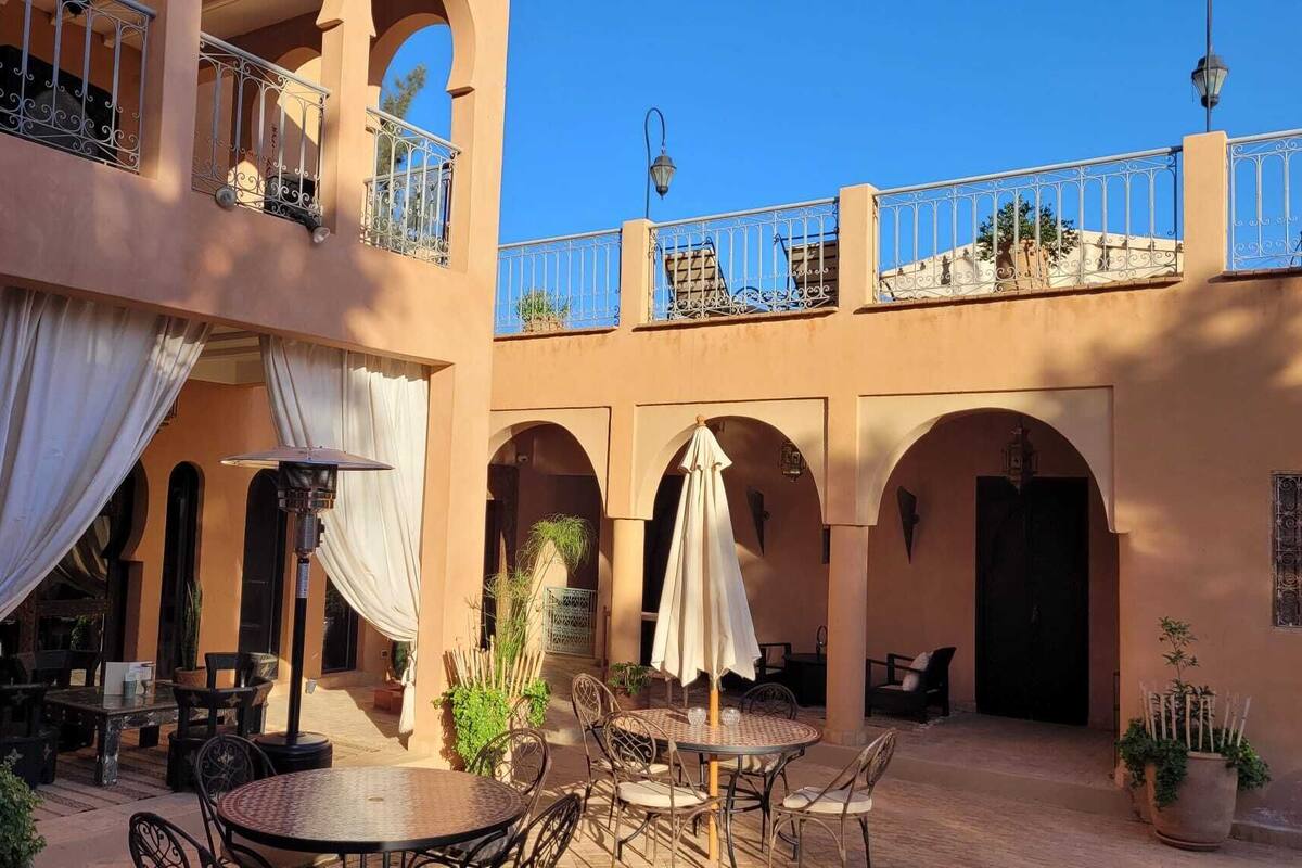A courtyard with outdoor seating, arches, and a balcony with decorative railings.