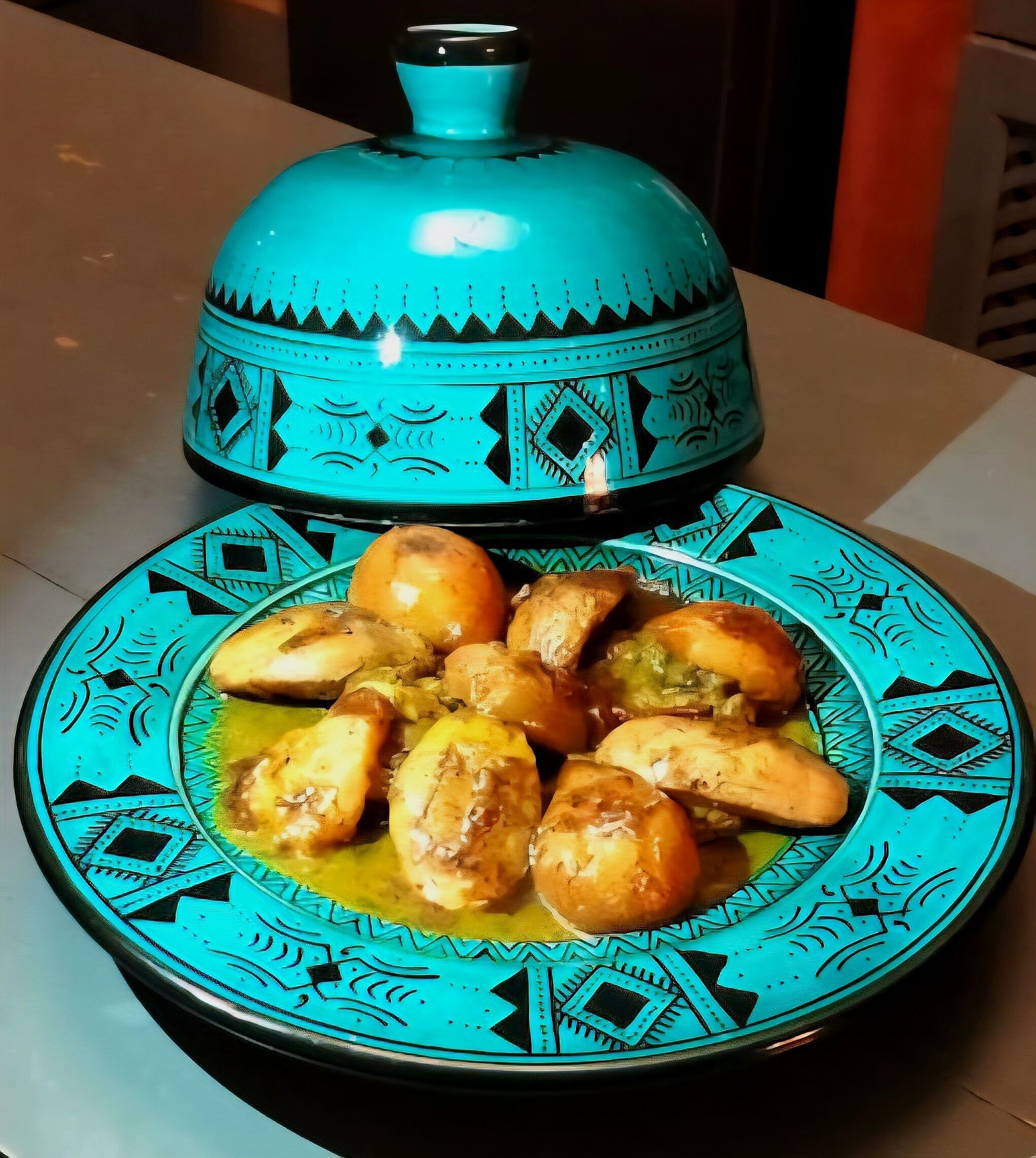 A plate of chicken pieces with a decorative blue and black patterned plate and a matching blue pot.