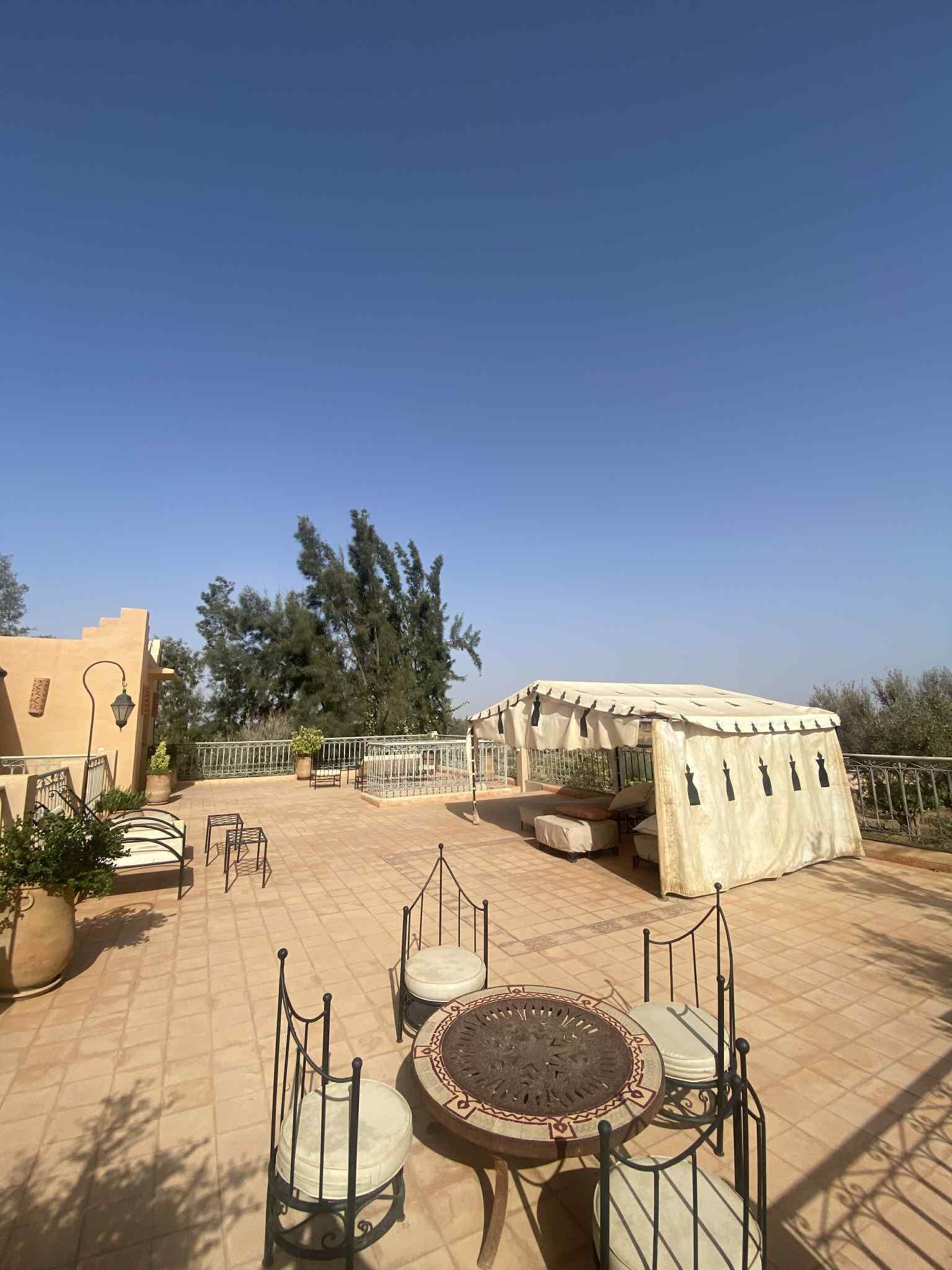 Una terraza en la azotea con mobiliario exterior, una zona techada y vistas del paisaje circundante.