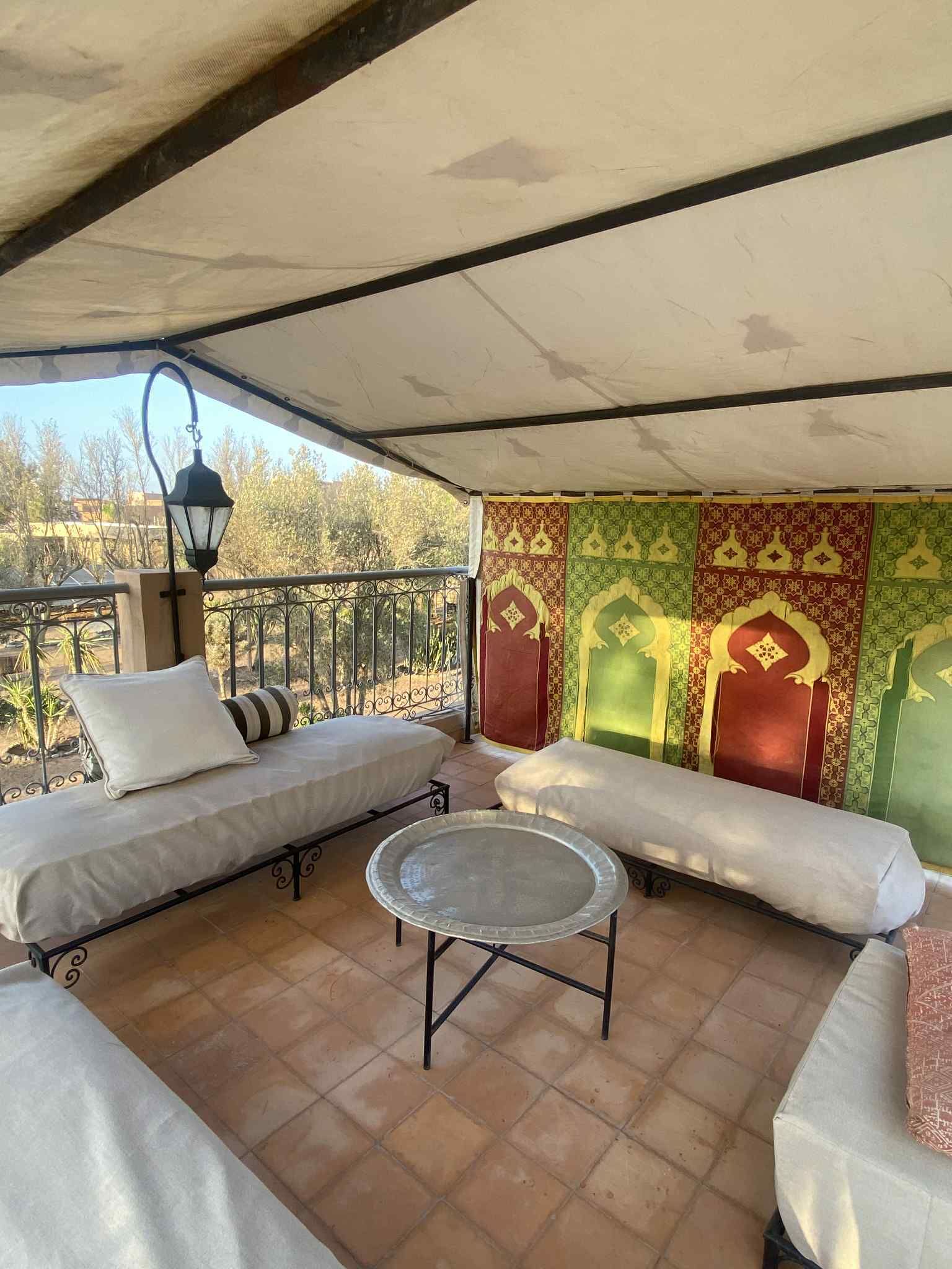 Un espacio de estar al aire libre cubierto con dos sofás, una mesita redonda y un muro decorativo.
