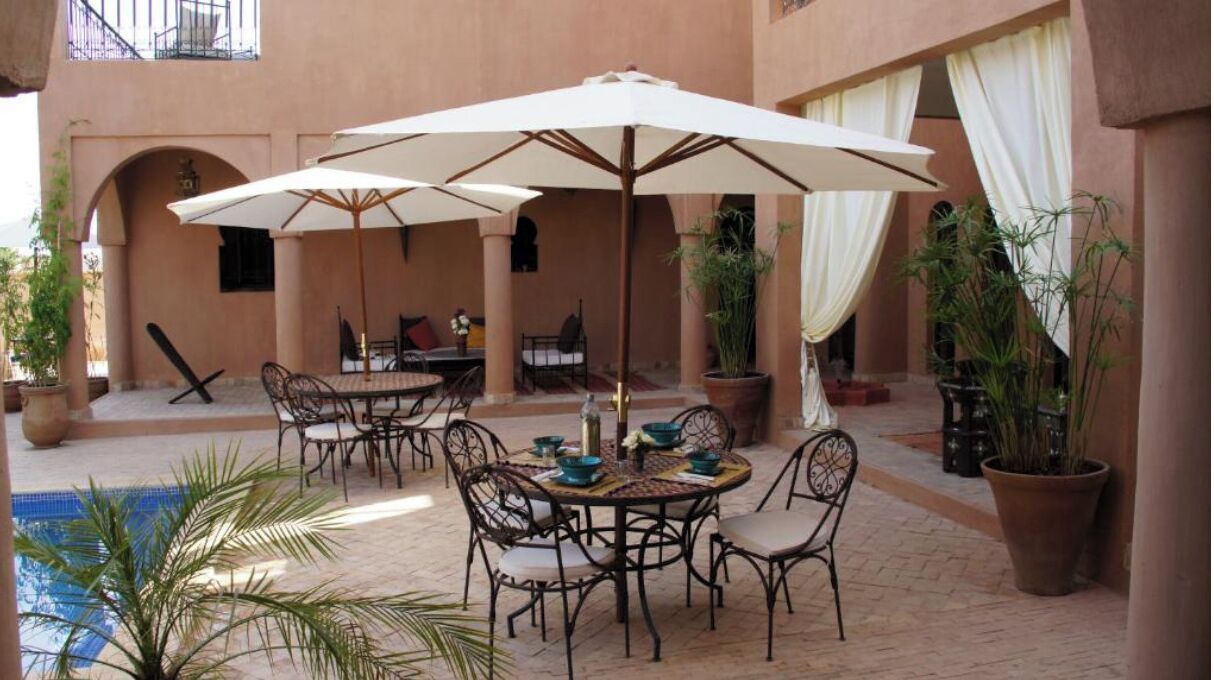 An outdoor patio with tables and chairs, umbrellas, and potted plants.
