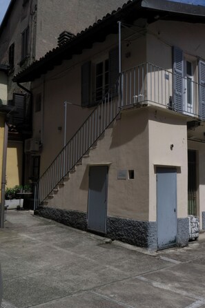 A building with a staircase leading to a balcony, a door, and a small window. - Borgovico Green Apartments (Como)
