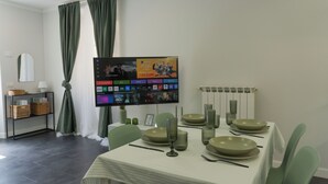Een eetgedeelte met een tafel gedekt voor vier personen, een flatscreen televisie aan de muur en een buffetgedeelte met manden en een spiegel.