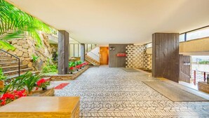 A spacious lobby with a stone wall, a staircase, and a patterned floor.