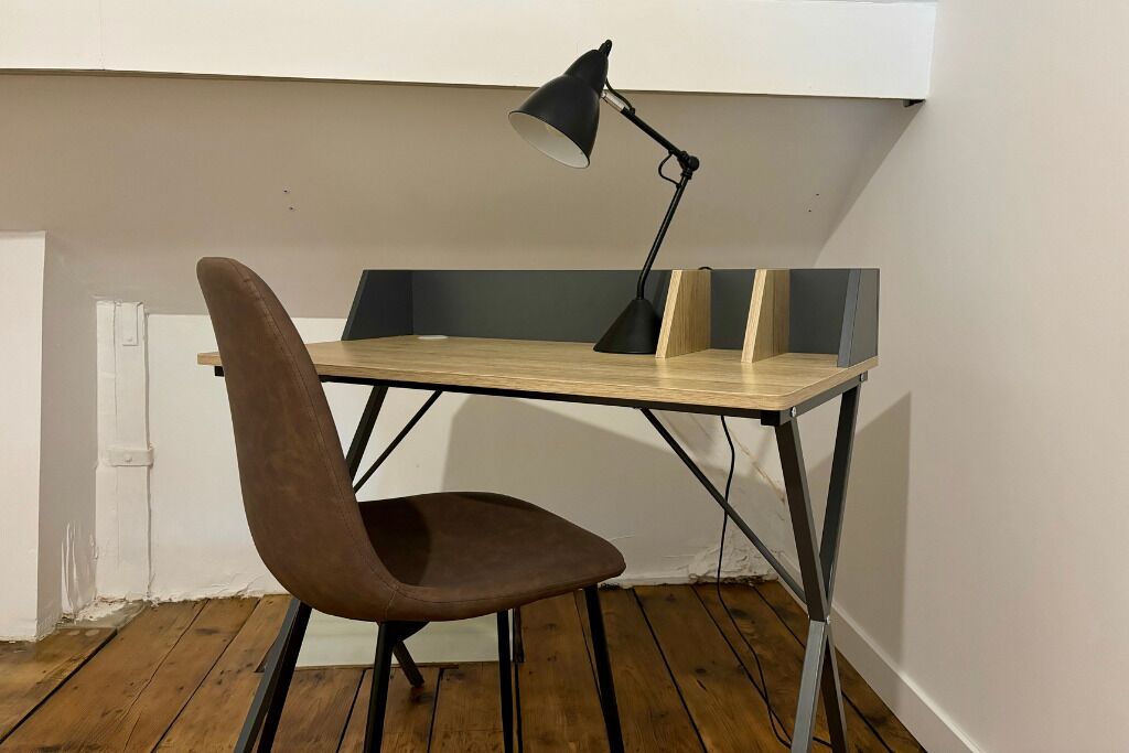 A corner workspace with a desk, chair, and a desk lamp.
