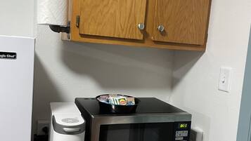 A kitchenette with a microwave, a Keurig coffee maker, and a wooden cabinet above.
