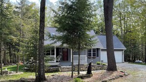 A house surrounded by trees with a porch and a stone wall.