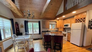 A kitchen with wooden cabinets, a refrigerator, and a dining area with chairs and a table.
