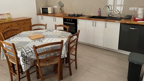Une cuisine de taille réduite comprenant une table à manger, des chaises, un four à micro-ondes, une cuisinière et un évier.