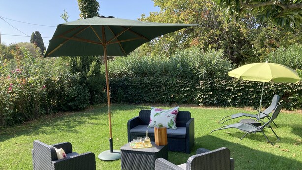 Un espace patio aménagé avec des meubles en osier, une table avec des boissons et deux parasols.