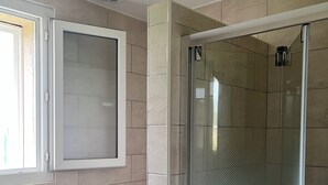Une salle de bain comprenant des toilettes, un espace douche et une fenêtre.