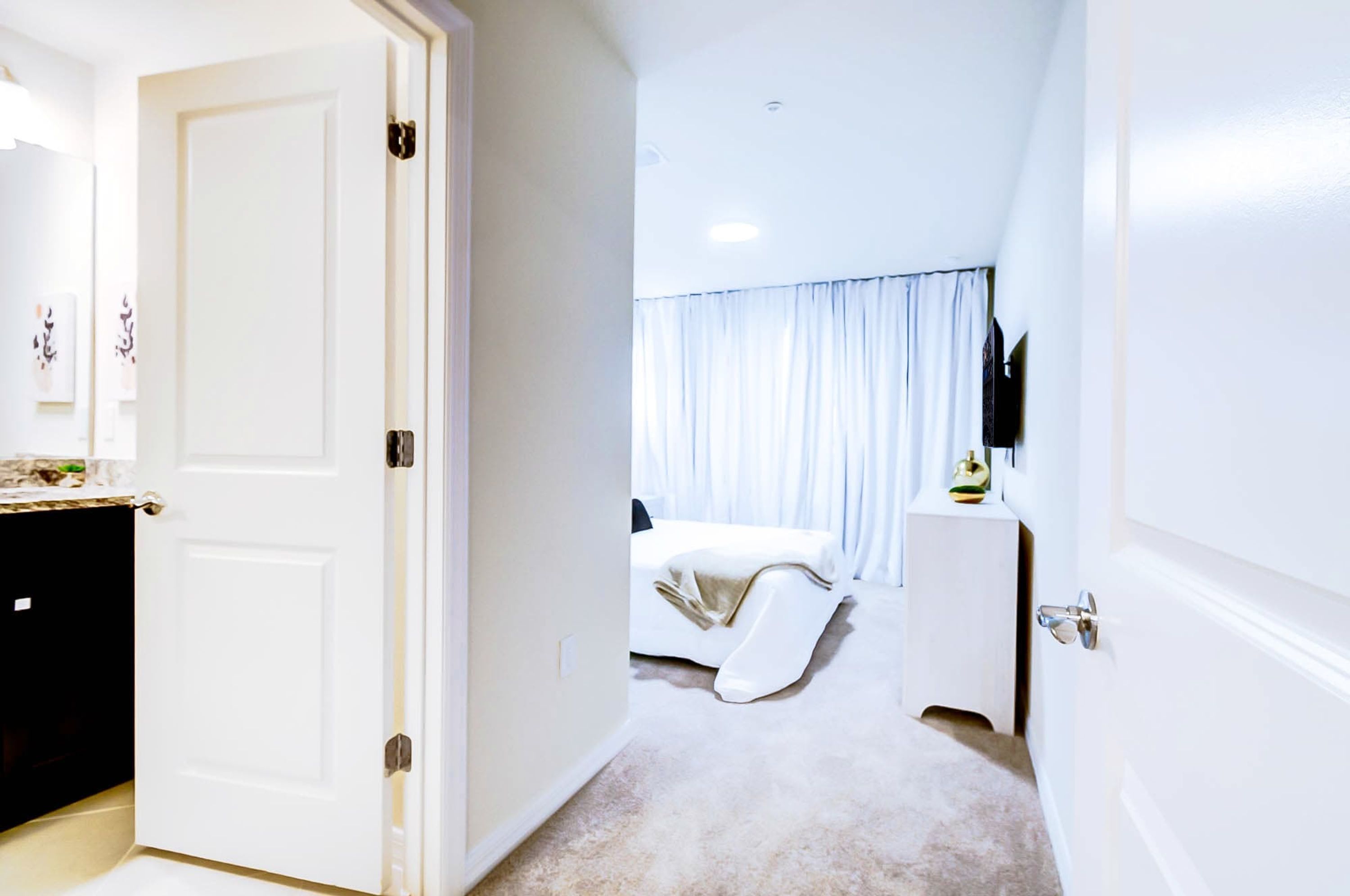 Une chambre d’hôtel comprenant un lit, une petite table de chevet, une télévision et une salle de bain avec des toilettes et un lavabo.
