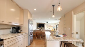Een moderne keuken met een centraal eiland, houten vloeren en inbouwapparatuur.