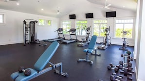 Un gimnasio amplio con cintas de correr, bicicletas estáticas y bancos de pesas.