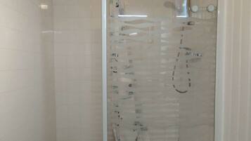 Eine Duschkabine mit Glaswänden, einer Handbrause und einem am Wand montierten Wasserhahn.
