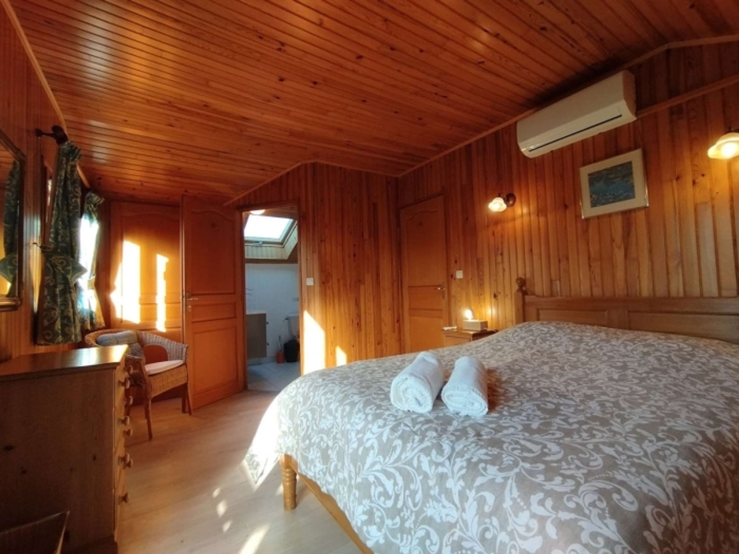 A wooden-paneled room with a bed, a desk, and a chair.