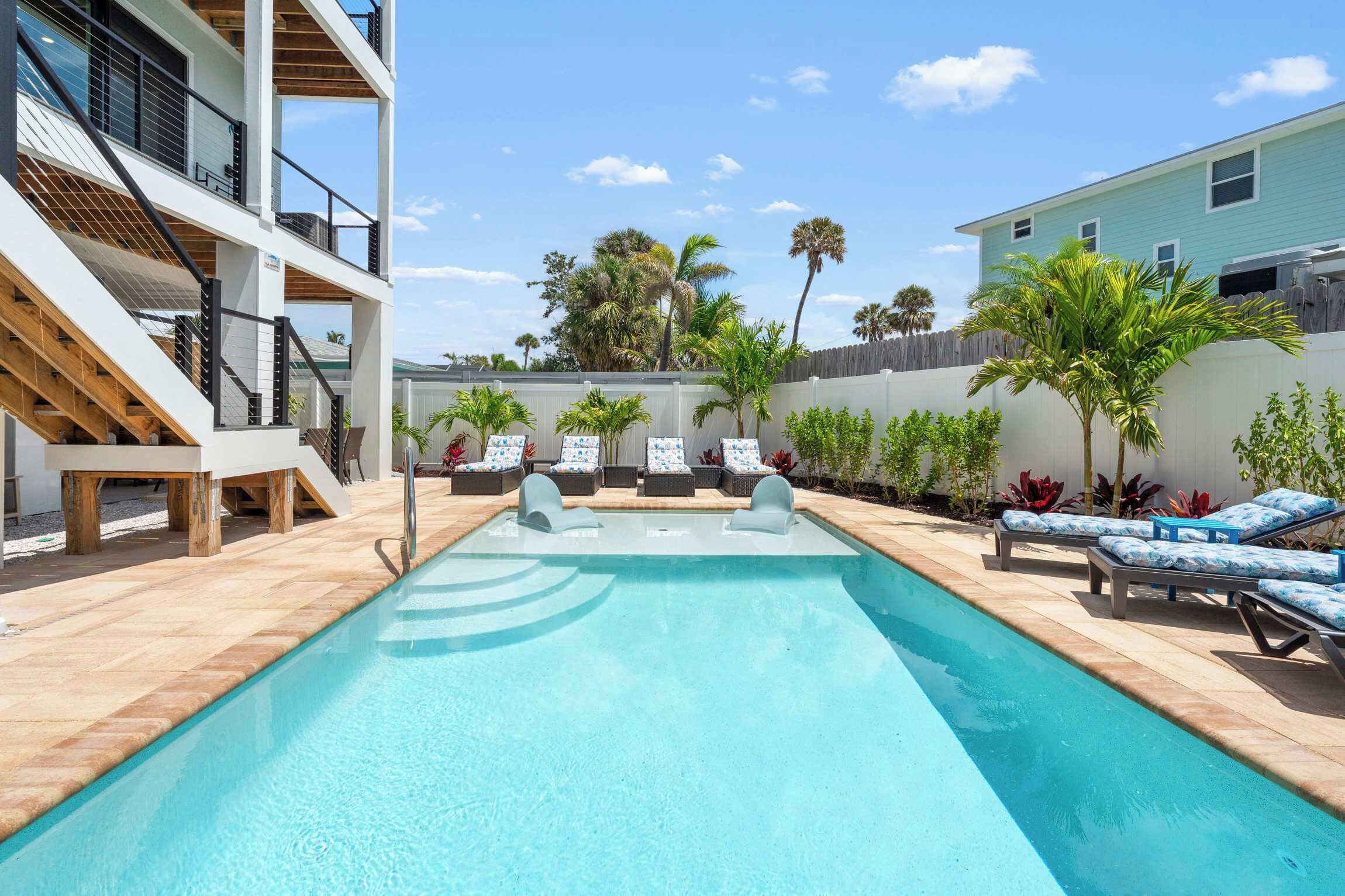 A swimming pool with lounge chairs and a wooden deck.