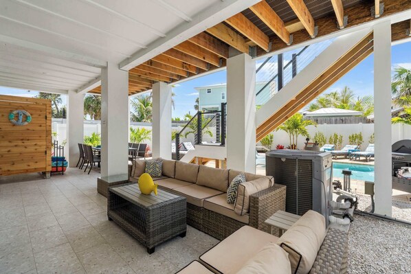 Ein Außenbereich mit einer Terrasse, einer Couch, einem Couchtisch und einem Pool im Hintergrund.