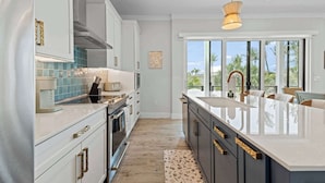 Una cocina moderna con armarios blancos, una isla grande e iluminación colgante.