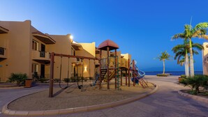 A playground with swings and slides, a covered play area, and a view of the ocean. - ALAHLAM CHALET YANBU (Yanbu)