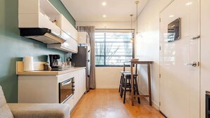 A compact kitchen with modern appliances, a dining area with stools, and a view through a window. - G102 - Stylish 1-Bed in Granada | Fast WiFi Included (Cali)