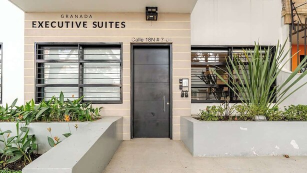 A building entrance with a sign reading "GRANADA EXECUTIVE SUITES" and a door labeled "Calle 18N # 7". - G102 - Stylish 1-Bed in Granada | Fast WiFi Included (Cali)