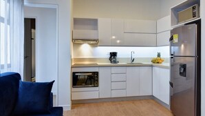 Una cocina moderna con armarios blancos, horno empotrado, cafetera y refrigerador.