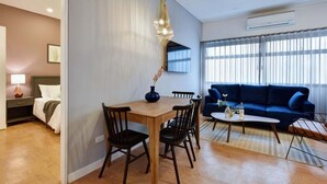 Una sala de estar moderna con comedor, un sofá azul y una mesa de comedor de madera con sillas.