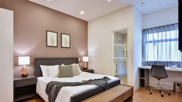 Un dormitorio con una cama, mesitas de noche, un escritorio y una silla.
