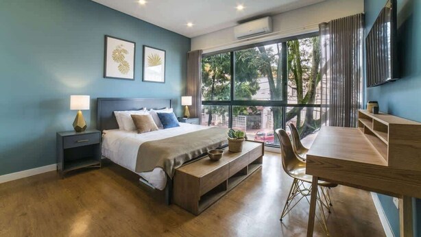 Camera da letto moderna con un letto grande, comodini, una scrivania e una finestra con vista sugli alberi.