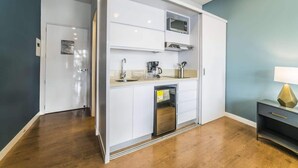 Una cucina compatta con forno a microonde, macchina del caffè e un piccolo frigorifero.