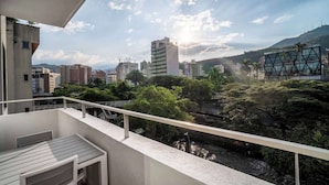 A balcony with a view of a cityscape, including buildings and greenery.