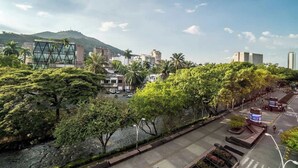 A cityscape with modern buildings, a river, and lush greenery.
