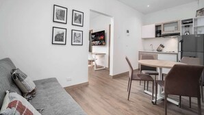 A modern living room with a grey sofa, a dining area with a table and chairs, and a kitchen with a refrigerator and microwave. - M202 - Río Bulevar | Zona Rosa and Historic Center (Cali)
