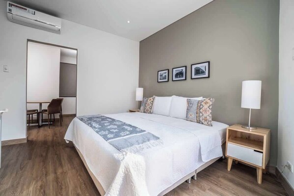 Un dormitorio con cama, mesitas de noche, escritorio y sillas.