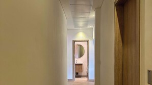 A hallway with wooden flooring and a wooden door on the right.