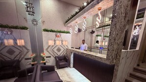 A reception area with a marble counter, seating, and a staircase. - Hotel Varishtta (Navi Mumbai)