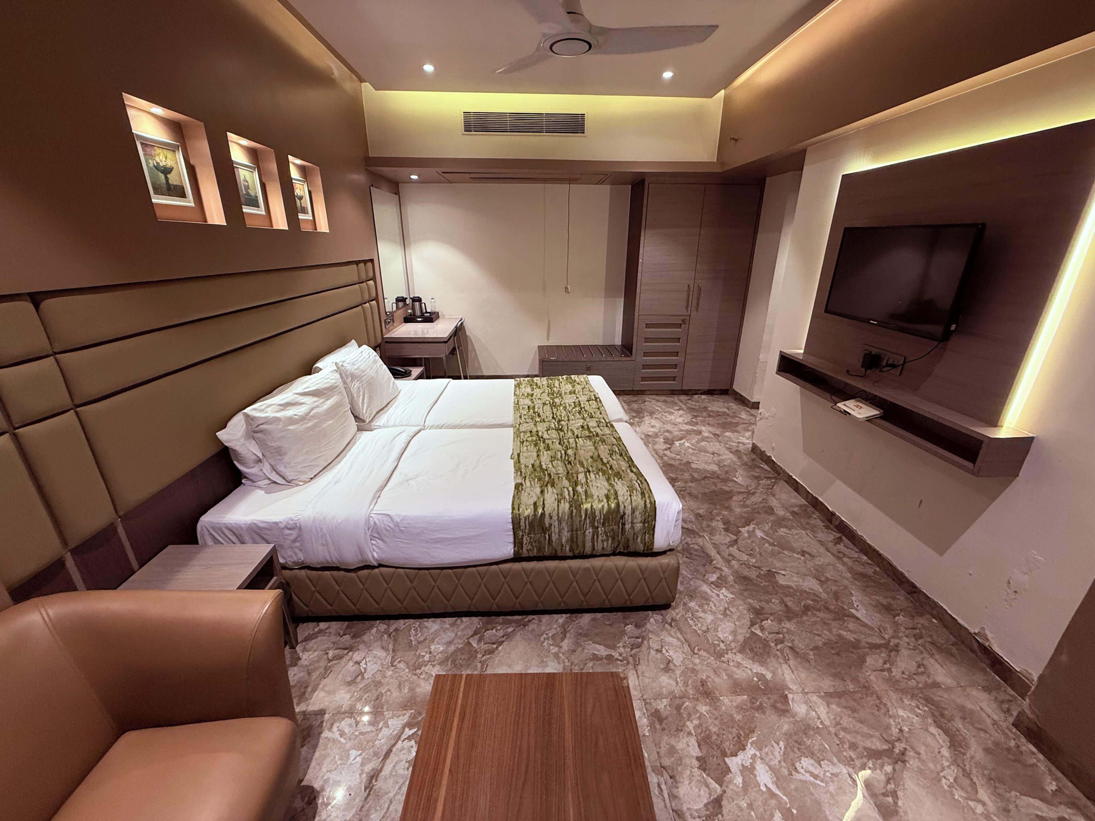 Moderni hotellihuone, jossa on sänky, televisio, työpöytä ja tuoli.