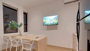 Een moderne vergaderruimte met een houten tafel, witte stoelen, een groot scherm en een plant.