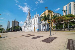 A cathedral with intricate architecture, a paved plaza, and modern buildings in the background.