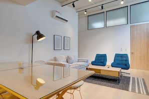A modern meeting room with a glass table, chairs, a sofa, and two blue armchairs. - M502 | Amazing 2-Bed Apartment | River Boulevard (Cali)