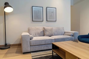 A modern living room with a sofa, a coffee table, a floor lamp, and two framed artworks on the wall. - M502 | Amazing 2-Bed Apartment | River Boulevard (Cali)