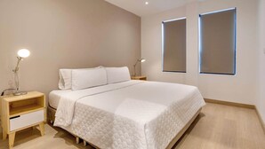 A modern bedroom with a large bed, bedside tables, and two wall-mounted windows.