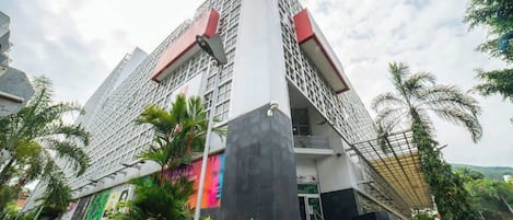 Un edificio moderno con una entrada destacada y un cartel direccional que indica 'HOTEL'.