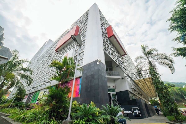 A modern building with a prominent entrance and a directional sign indicating 'HOTEL'.