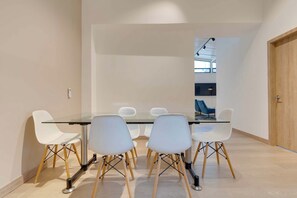 Une salle de réunion moderne avec une table en verre et des chaises blanches aux pieds en bois.