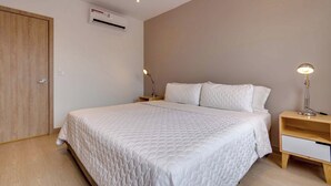Un dormitorio con cama, mesitas de noche, un equipo de aire acondicionado y una puerta.