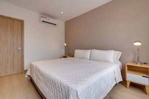 A bedroom with a bed, bedside tables, an air conditioning unit, and a door. - M502 | Amazing 2-Bed Apartment | River Boulevard (Cali)